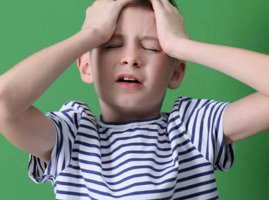 child with pediatric migraines holding his head
