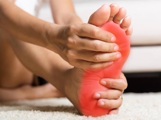 person with neuropathy holding painful foot